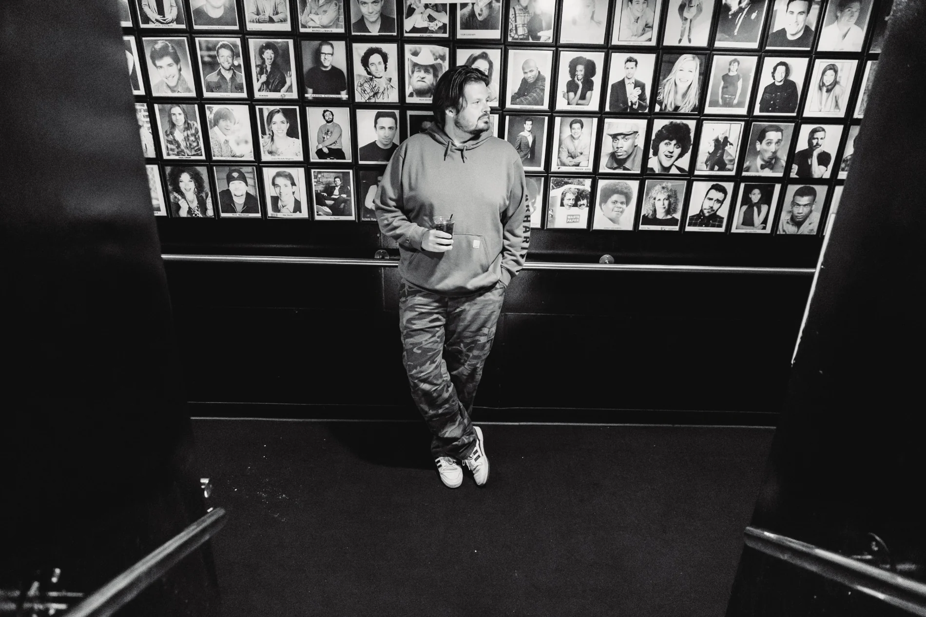 Matt Lockwood standing in front of a wall of comedy portraits